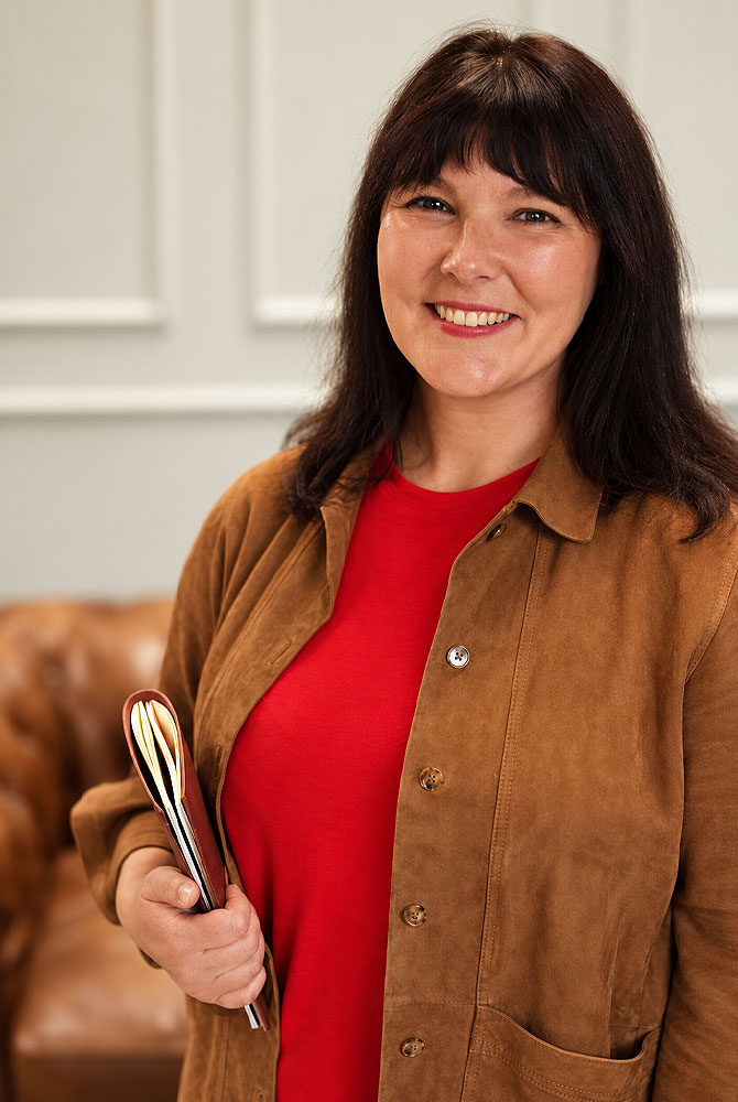 Jess Lorimer, founder of Selling to Corporate, holding a notebook.